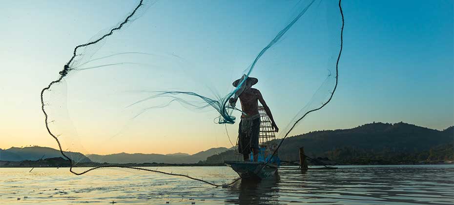 Ein Fischer mit Netz am Wasser